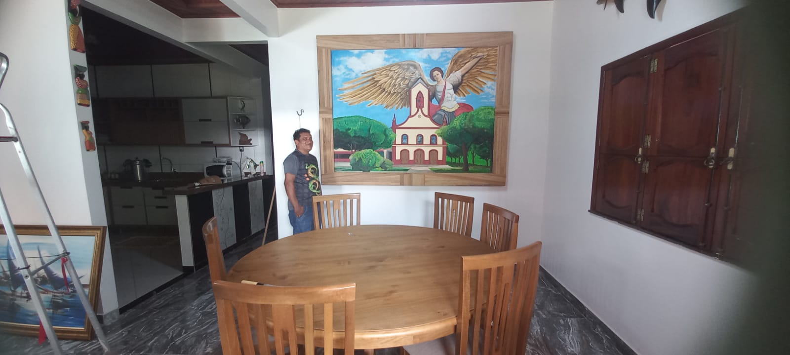 Quadro de um anjo sobre uma capela, instalado na parede de uma sala.